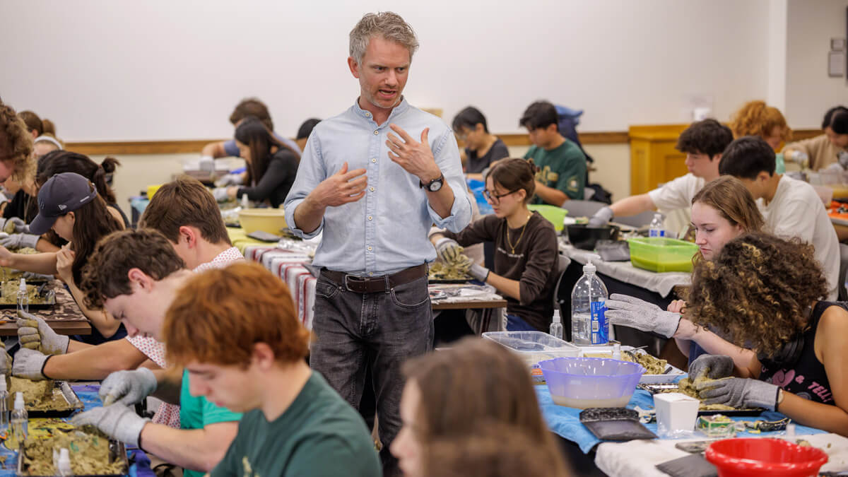 Ceramics expert Coleton Lunt speaks while walking among the tables of participants.
