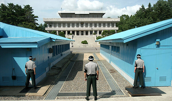 Three soldiers stand at the DMZ separating North and South Korea. Photo by Henrik Ishihara Globaljuggler and distributed through Wikimedia Commons.